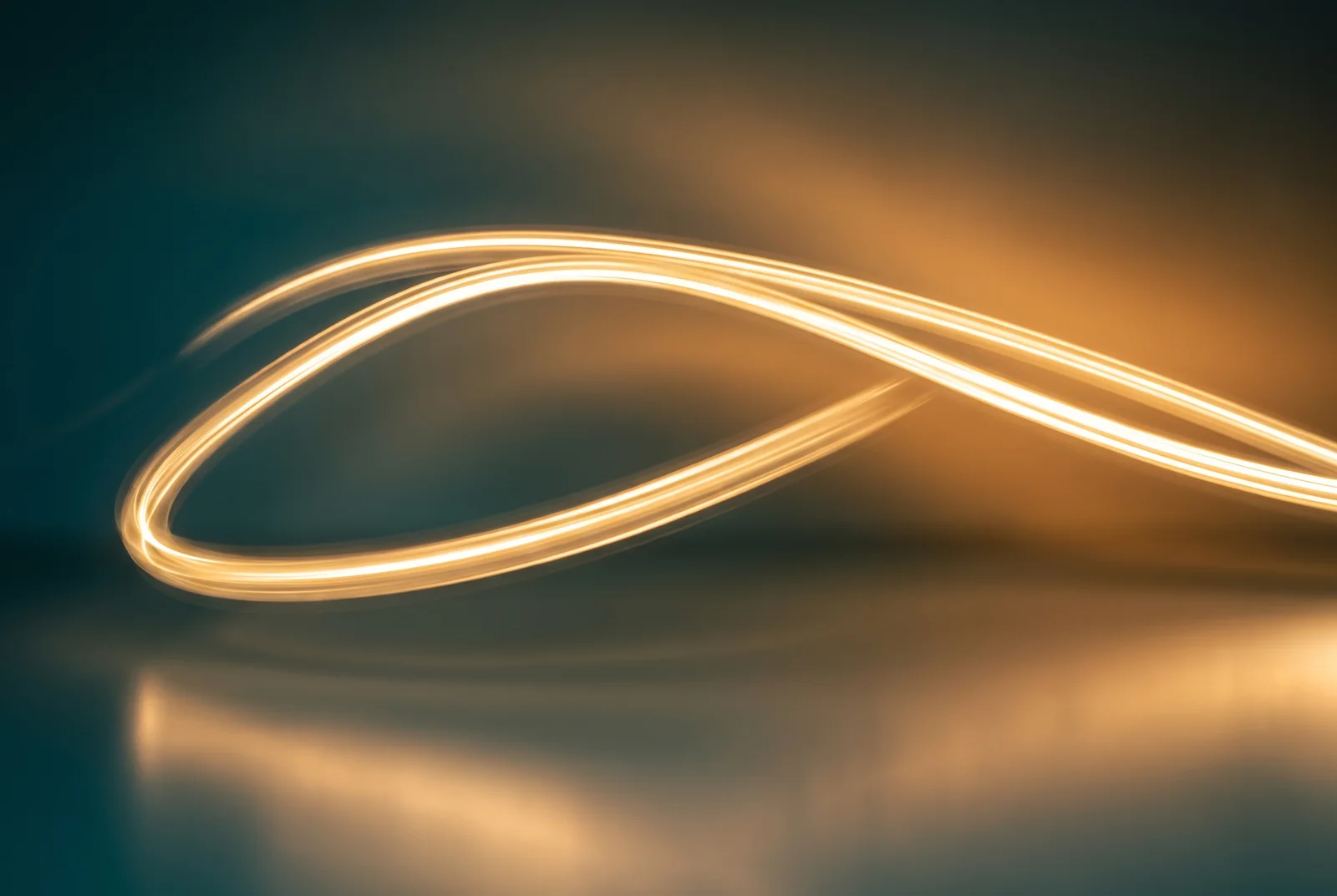 A single ribbon of golden light sweeping in a smooth arc across a teal-to-amber background.
